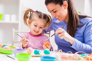 Fototapeta premium Happy mother and daughter coloring eggs for Easter.