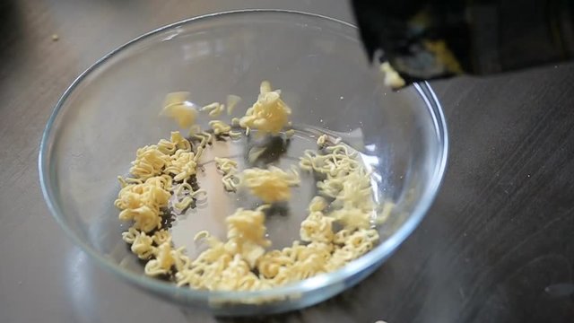 Water is poured into a plate with instant ramen noodles - closeup