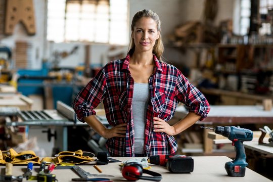 Portrait of female carpenter standing with hand on hip