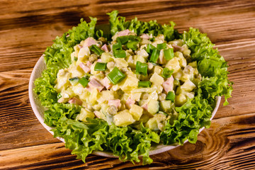 Ceramic plate with russian traditional salad olivier on wooden table
