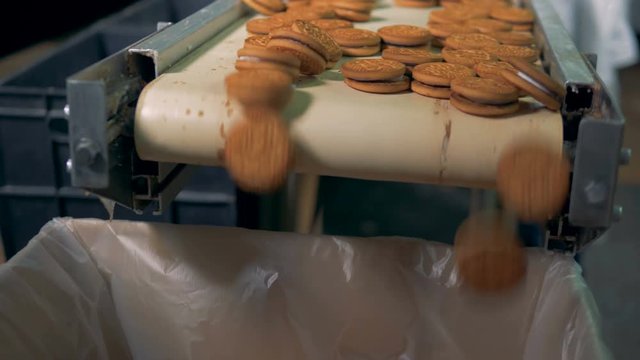 Worker sorts sweet cookies on manufacturing line. Sweet bakery on production line at food factory. Bakery production at food factory. Food products production