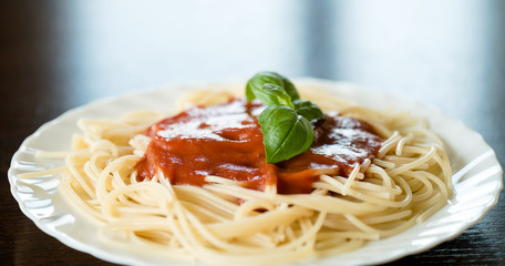 Italian pasta spaghetti topped with a tomato and fresh basil