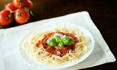 Italian pasta spaghetti topped with a tomato and fresh basil