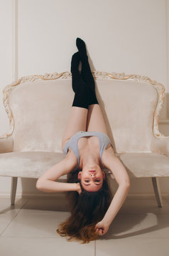 Young beautiful brunette woman with perfect body in sexy grey underwear and stockings, posing on gray background. Studio shoot