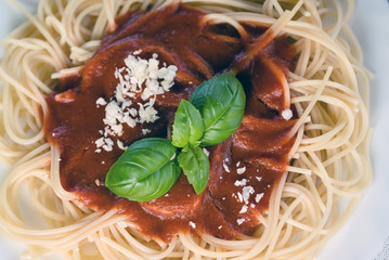 Italian pasta spaghetti topped with a tomato and fresh basil