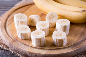Slices of a banana on a cutting board on a wooden table