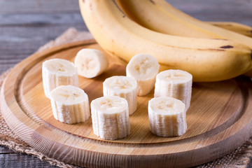 Slices of a banana on a cutting board on a wooden table