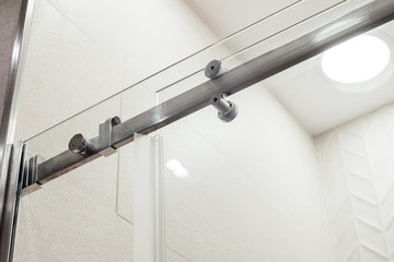 Closer metal structure of the upper fasteners and rollers for the sliding glass door in the shower view in white the interior
