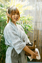 Onsen series: Asian woman holding wooden bucket in onsen