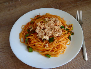 Spaghetti with tuna fishand vegetable  sauce in the plate, wooden table, top view