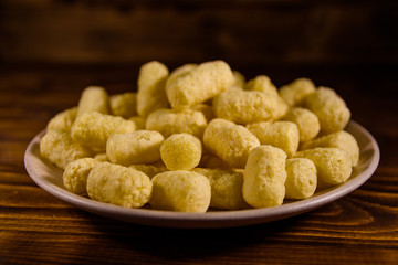 Ceramic plate with corn sticks on wooden table