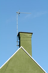 Chimney stack and tv aerial on roof of house - the render on this property has been painted a deep green colour