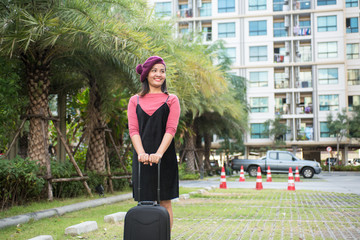travel, business trip, and people concept - Portrait of a well dressed business woman pulling suitcase outdoors..