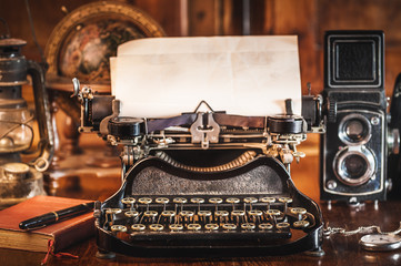 vintage photography still life with typewriter, folding camera, globe map and book on a wood table.