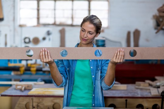 Female carpenter checking a wooden plank
