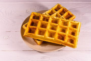 Ceramic plate with belgian waffles on wooden table