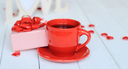 Cup of coffee and gift on blurred background.