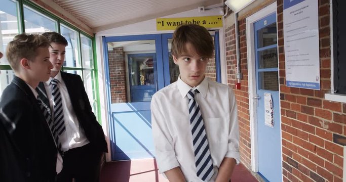 4K Young boy at school with no friends, walking through hallway with other kids staring at him. Slow motion