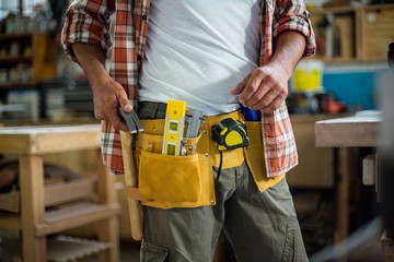 Carpenter removing hammer from tool belt