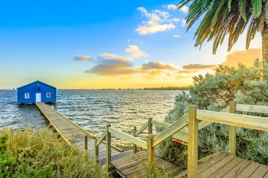 The iconic landscape of Blue Boat House or Crawley Edge Boatshed with wooden jetty on Swan River at sunset light. One of the most photographed locations in Perth, Western Australia, near Kings Park.