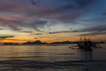 Fototapeta na wymiar traditional philipinian boat silhouette in El Nido, Palawan with colored sunset on background