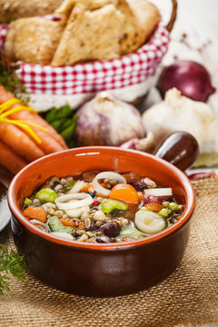 Rural vegetarian broth soup with colorful vegetables and rustic clay pot.