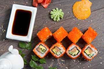 Sushi rolls served on a wooden plate in a restaurant. Sushi rolls and caviar on black wooden table. Japanese food.