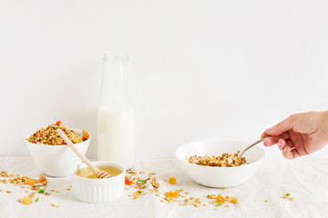Granola, a bottle of milk and honey  on the table