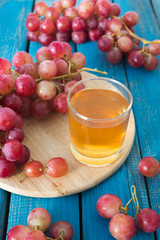 A glass of fresh grape juice and red grapes