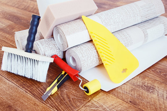 Composition with various tools for home repair and rolls of wallpaper on wooden background