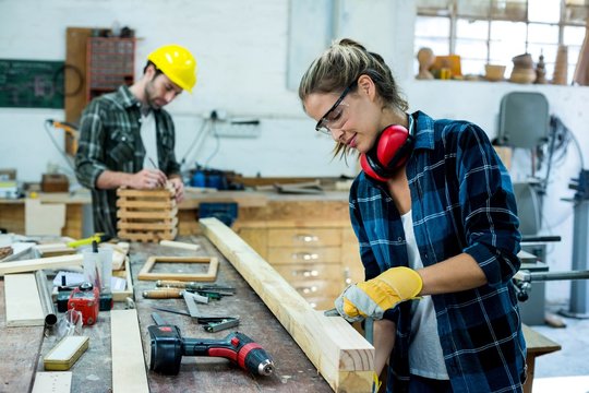 Male and female carpenters working in workshop