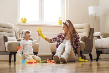 Little girl and  mother cleaning home together and having fun.