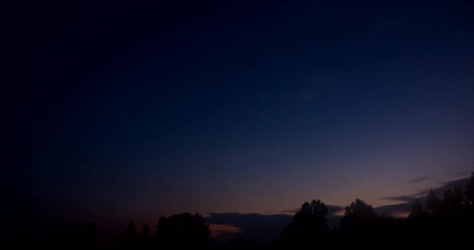 Time lapse of nightfall and the movement of clouds over the forest.
