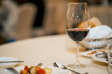 glass of red wine and dinner on a set table. a restaurant. waiting for the meeting