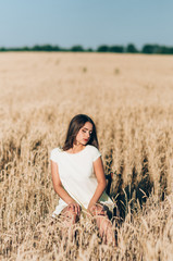 The girl walks on a wheat field on a summer evening