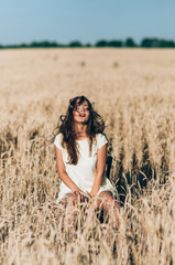 Naklejka na ściany i meble The girl walks on a wheat field on a summer evening