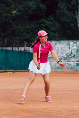 Obraz premium Tennis player. Full length photo of beautiful young woman playing tennis, waiting to receive serve. Dressed in colorful sportswear.
