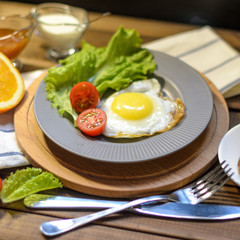 English Breakfast: fried egg, juice, cherry tomatoes, lettuce, grain bread, sauce, top view.
