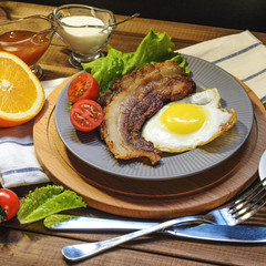English Breakfast: fried egg with bacon, orange juice, tomatoes, zernovoi bread, lettuce leaf, top view.