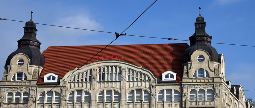 Fassade des ehemaligen Kaufhauses "R&ouml;mischer Kaiser" mit T&uuml;rmchen und rotem Dach vor strahlend blauem Himmel 