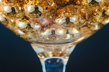 Gold beads in the wine glass with water, bubbles, macro, photo, background for design or Wallpaper.