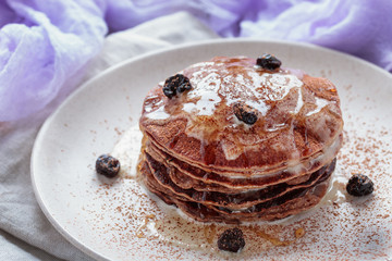 Homemade pancakes or russian blini with coconut cream, maple syrup and dried blueberries. Vegan dessert