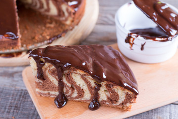 Piece of ''Zebra'' cake with chocolate glaze on wooden table