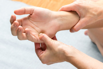 Chiropractor applying pressure on palm of female hand.