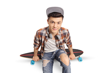 Teenage hipster sitting on a longboard and looking at the camera