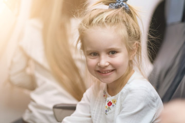 Young blonde girl smiling and looks at camera on tha aircraft board.