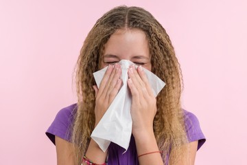 Cute young girl child sneezing in a tissue blowing his runny nose.