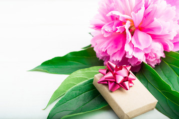 Holiday present of craft paper for woman with pink flower and green leaves over white background