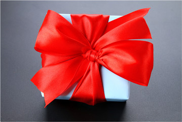 Gift blue box with a red bow on a gray background.