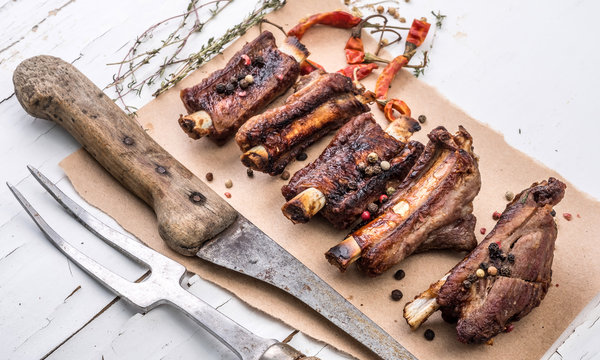 Delisious homemade pork ribs on a piece of brown pape with carving fork and spices, close-up